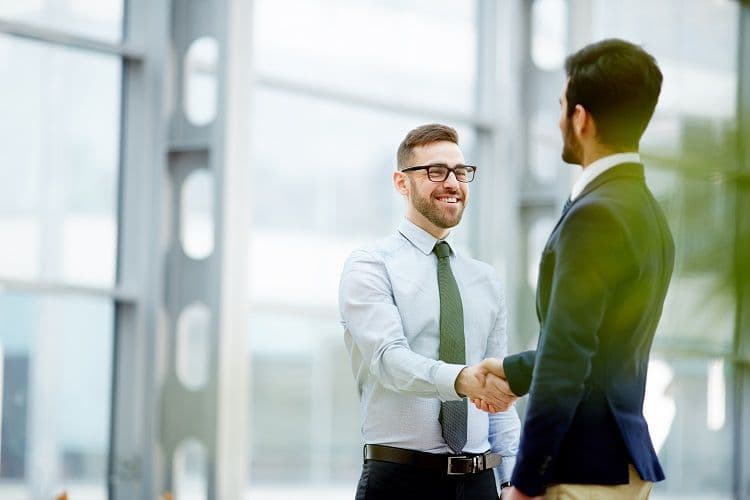 Neue Zusammenarbeit im HR-Bereich: Lohnabrechnung professionell organisiert Zwei Männer in Businesskleidung geben sich zur Begrüßung oder Vertragsbesiegelung die Hand