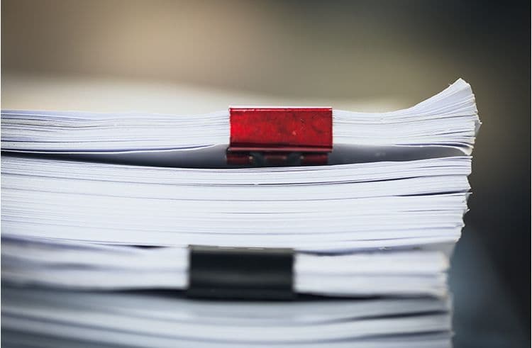 Papierstapel mit Klammern – Dokumentenorganisation in der Lohnbuchhaltung Zwei große Papierstapel, jeweils mit einer roten und schwarzen Klammer geheftet – typische Dokumente aus der Lohnbuchhaltung