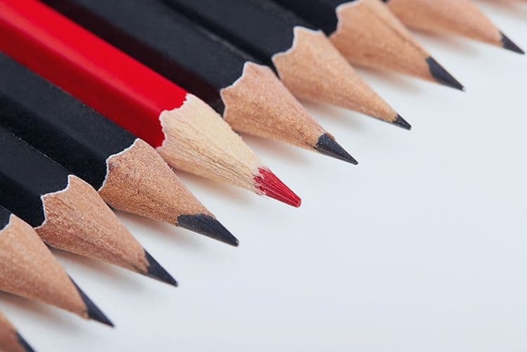 Sonderregelungen in der Lohnbuchhaltung: Wenn Standard nicht ausreicht Roter Bleistift hebt sich zwischen schwarzen Bleistiften ab – Symbol für Individualität in der Abrechnung