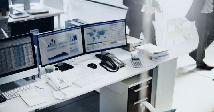 Digitaler Arbeitsplatz in der Lohnbuchhaltung mit Monitoring-Tools und Finanzkennzahlen Moderner Schreibtisch mit mehreren Monitoren, die Diagramme, Weltkarten und Finanzkennzahlen zeigen – digitales Arbeiten in der Lohnbuchhaltung