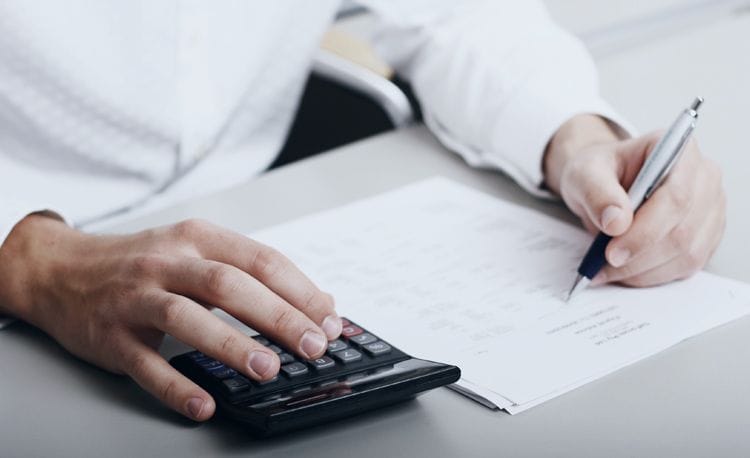 Person berechnet Zahlen auf einem Dokument mit Taschenrechner und Stift Nahaufnahme einer Person, die mit Taschenrechner und Stift Finanzunterlagen bearbeitet – symbolisiert Buchhaltung, Steuerberechnung und Finanzplanung