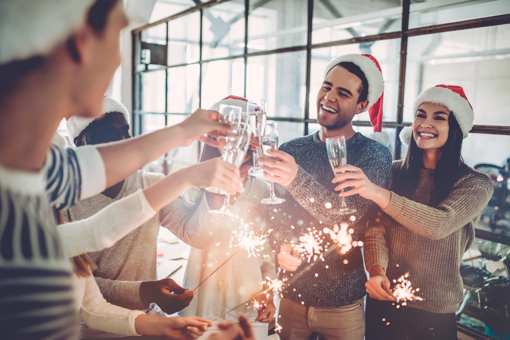 Mitarbeitende feiern Weihnachtsfeier mit steuerlichem Bezug zur Lohnbuchhaltung Fröhliche Mitarbeitende mit Weihnachtsmützen stoßen auf einer betrieblichen Weihnachtsfeier an – relevant für die Lohnbuchhaltung bezüglich steuerlicher Freibeträge