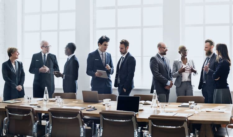 Strategische Entscheidungen in der Lohnbuchhaltung: Austausch auf Führungsebene Gruppe von Geschäftsleuten im Anzug im Gespräch vor einem Konferenztisch – Symbol für Payroll-Strategie und Unternehmensentscheidungen