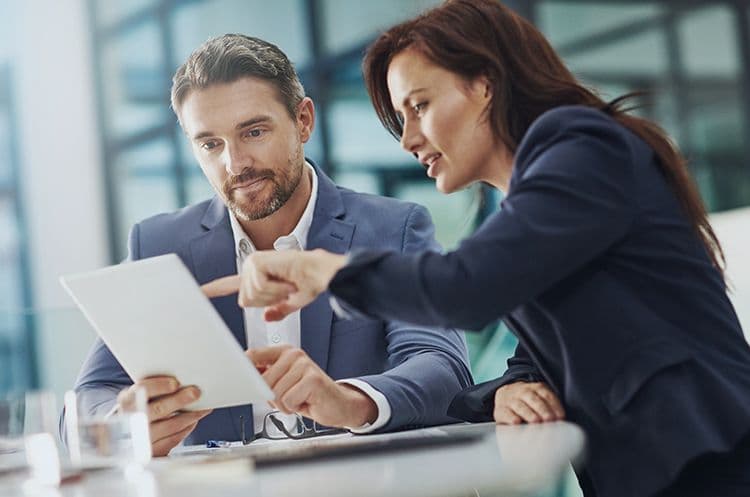 Teammeeting in der Lohnbuchhaltung zur Analyse von Abrechnungsunterlagen Zwei Kollegen in Businesskleidung analysieren gemeinsam ein Dokument auf einem Tablet – typische Besprechungssituation in der Lohnbuchhaltung