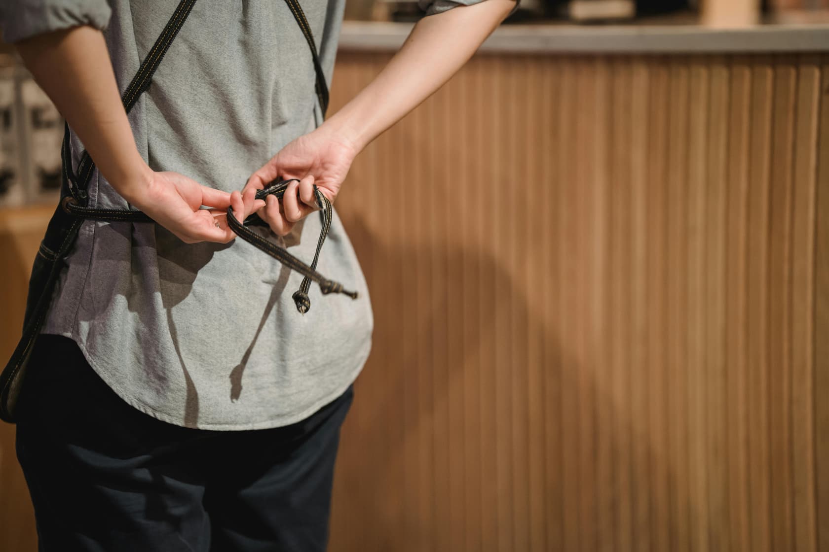 Blog Card Image Eine Person bindet sich die Schürze auf dem Rücken - Minijob und Feiertage