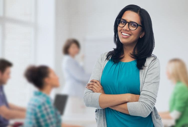 Payroll-Training für HR-Profis: Weiterbildung in der Lohnbuchhaltung Freundliche Frau mit Brille steht selbstbewusst vor einem Schulungsteam im modernen Büro