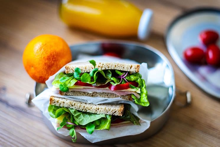 Steuerfreie Verpflegung als Benefit: Sachbezüge in der Lohnbuchhaltung Gesunde Brotzeit mit Sandwich, Orange und Saft als Symbol für steuerfreie Verpflegungszuschüsse