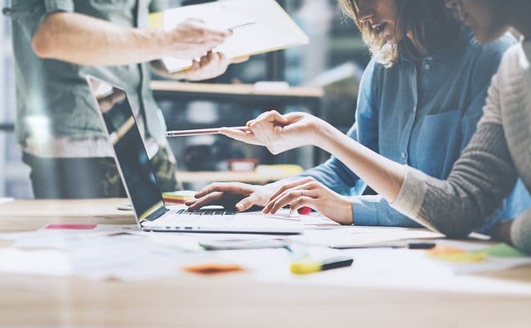 Team bespricht digitale Auswertungen im Rahmen der Lohnbuchhaltung Kolleginnen und Kollegen arbeiten gemeinsam am Laptop und diskutieren über Unterlagen – typische Situation in der Lohnbuchhaltung bei Abstimmung von Gehaltsdaten oder Auswertungen
